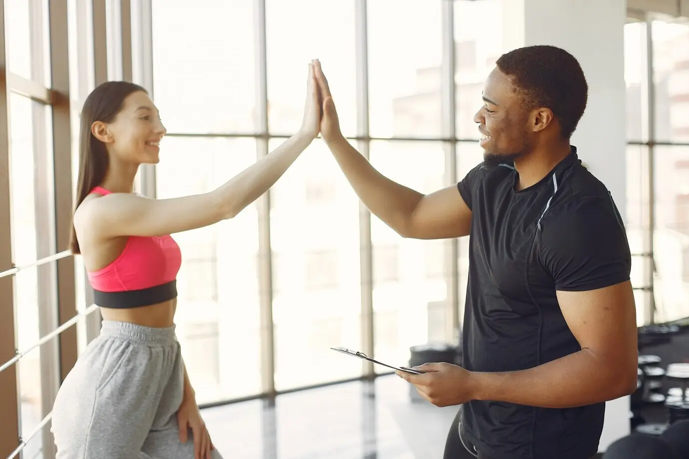 A young woman in a pink top stands with a coach.