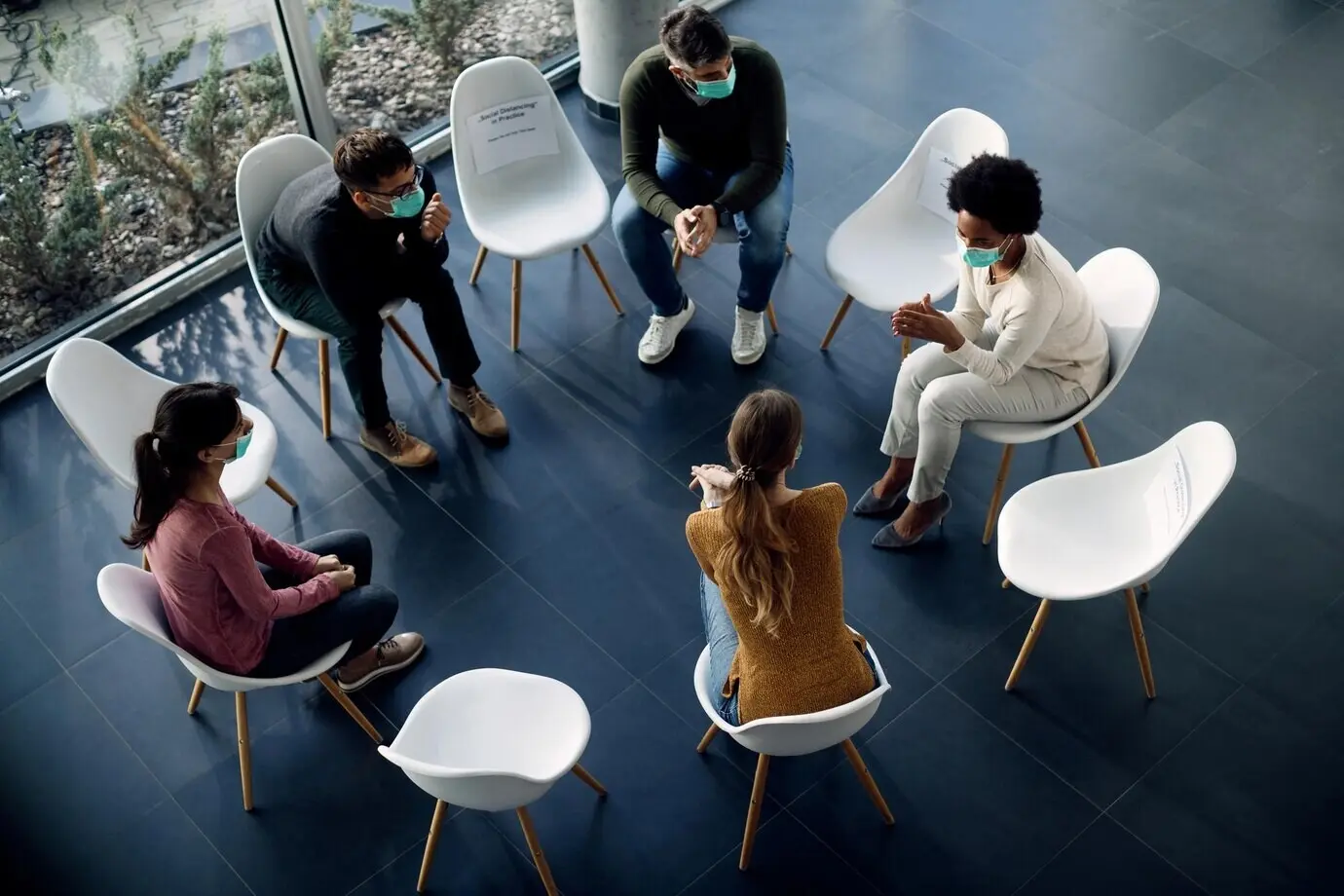 Overhead view of people wearing face masks during group therapy because of the coronavirus pandemic.